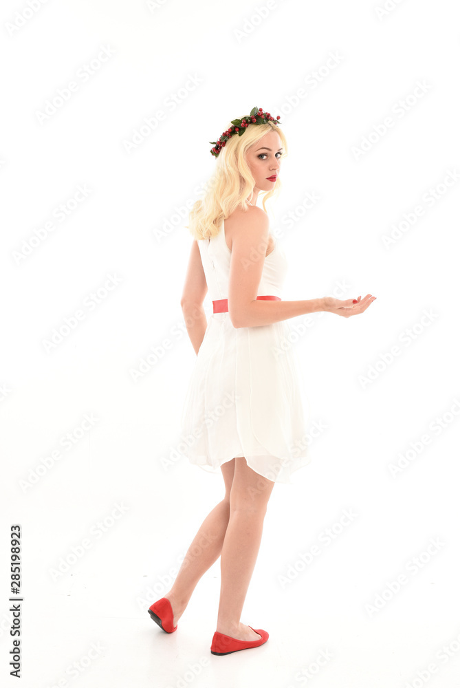 full length portrait of blonde girl wearing a white dress and flower crown. Standing pose, isolated against a white studio background. full length portrait of blonde girl wearing a white dress and flower crown. Standing pose, isolated against a white studio background.