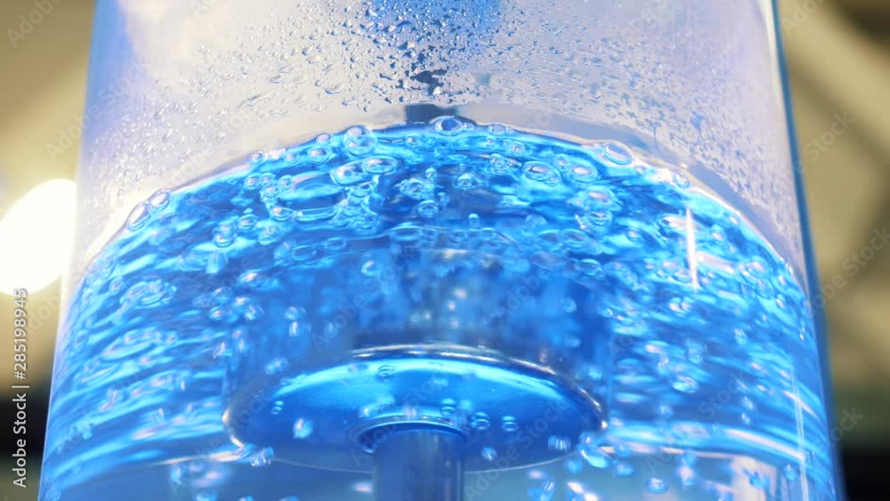 Boiling water in large glass cooler with a neon backlight and metal