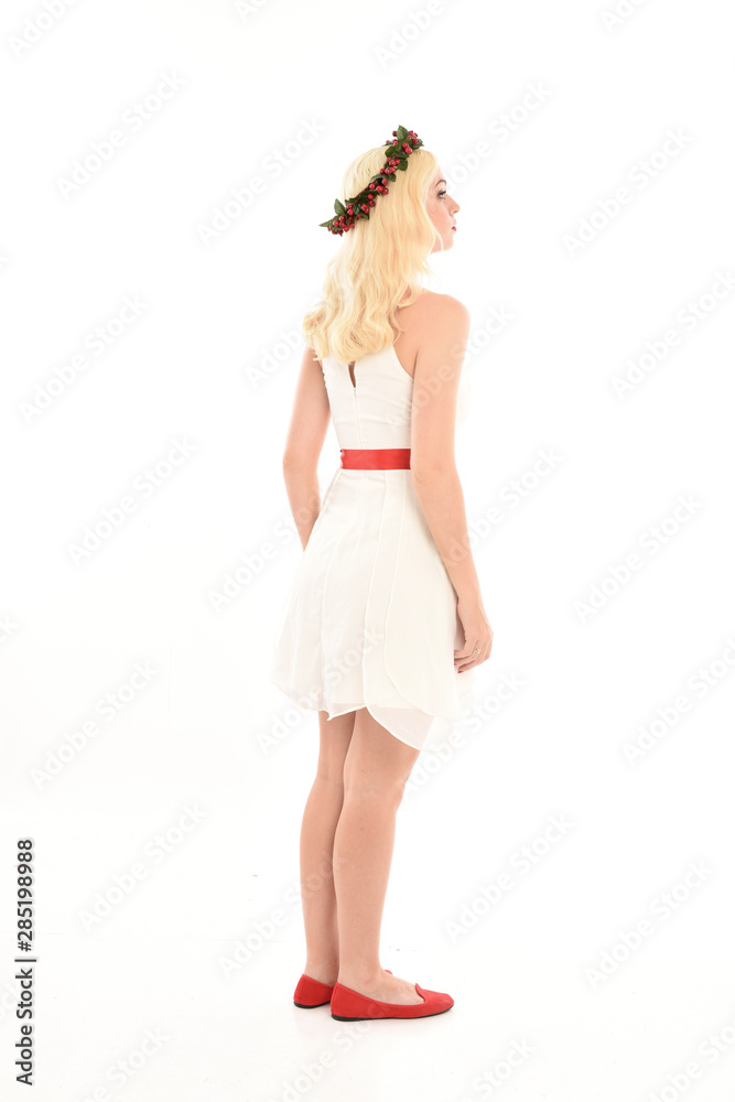 full length portrait of blonde girl wearing a white dress and flower crown.  Standing pose, isolated against a  white studio background.