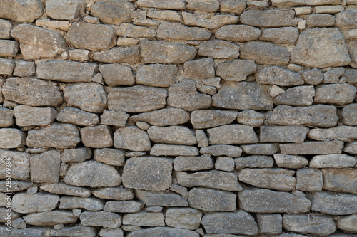 Old gray wall made of large and small rectangular hewn natural stones