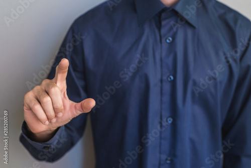 Man pointing his finger, close up, man in office shirt on grey background.