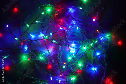 Christmas multi-colored lights. Electric LED lights are randomly laid out on a dark background. Decorative garland. Close-up