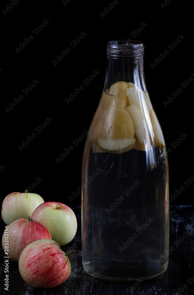 Apple kompot in glass bottle on black the background