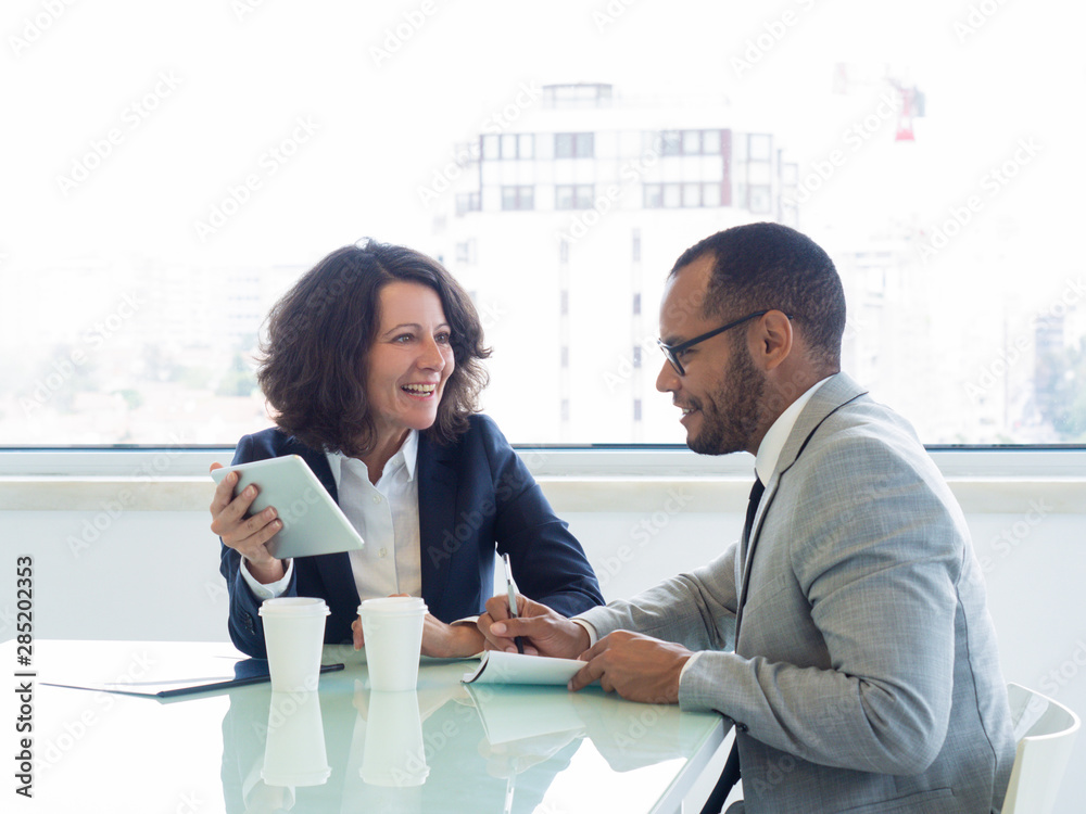 © Mangostar - Joyful successful mentor training intern. Happy business woman showing tablet screen to male colleague, he writing notes in notebook. Mentorship concept