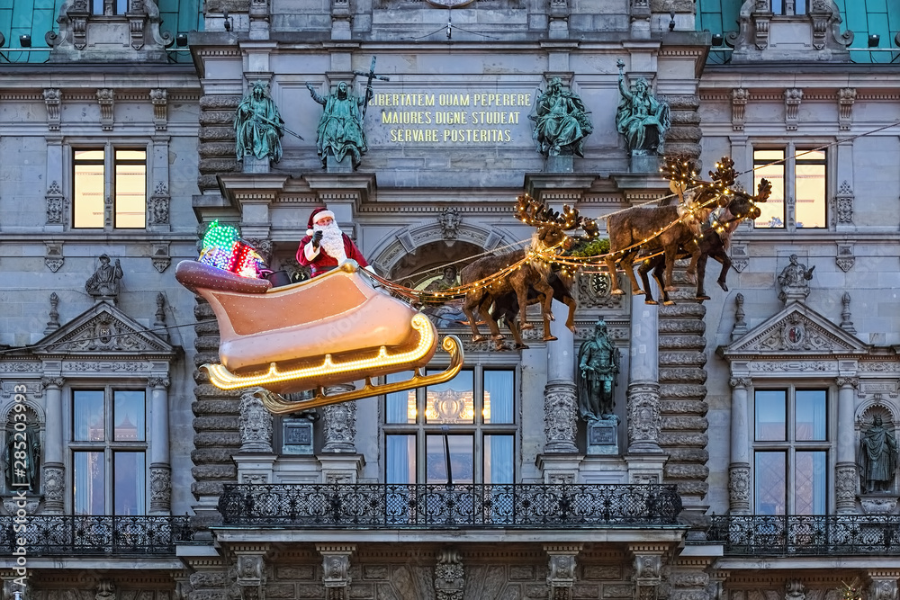 Hamburg, Germany. Flying Santa Claus on background of Hamburg Town Hall. Latin motto on facade reads: The freedom won by our elders, may posterity strive to preserve it in dignity.
