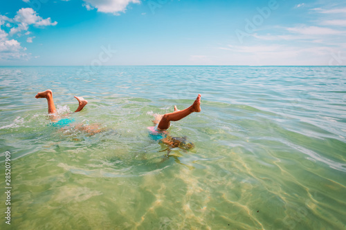 Canvas Print kids making handstand in sea, boy and girl divinig on beach