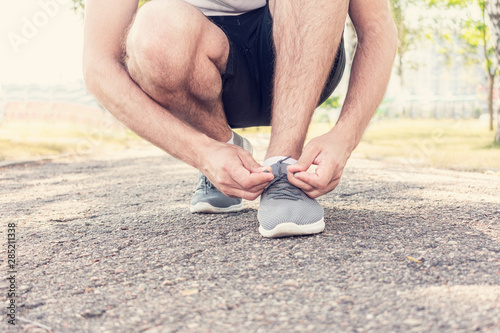 Man runner tying shoelaces, close up, cropped image, toned