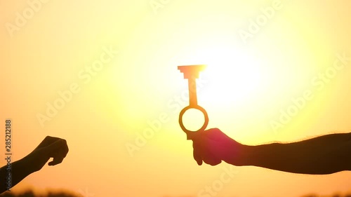 A man passes the key to a woman on the background of a beautiful sunset. Silhouette. Concept of construction and real estate transactions photo