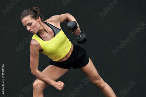 Sport woman doing back exercise workout with weights at gym