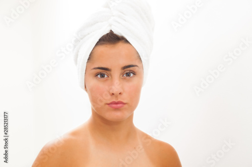 Portrait of a beautiful young woman in a bathroom. Youthful girl with perfect skin using facial cosmetics. Skin care and health concept..