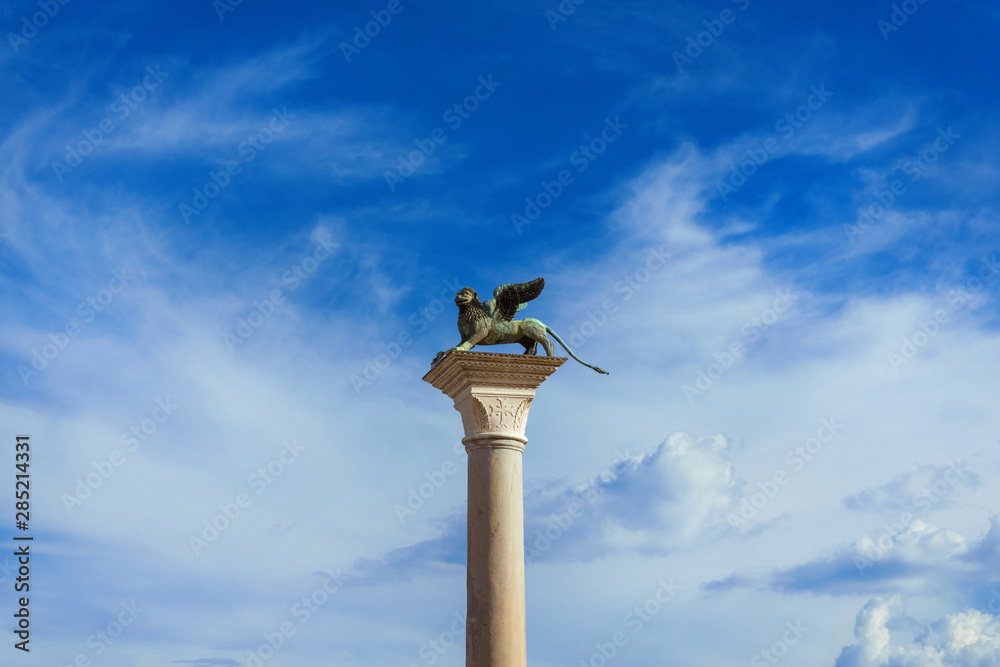 Saint Mark Winged Lion medieval statue, a symbol of the Old Venice Republic, at the top of an ancient column among clouds