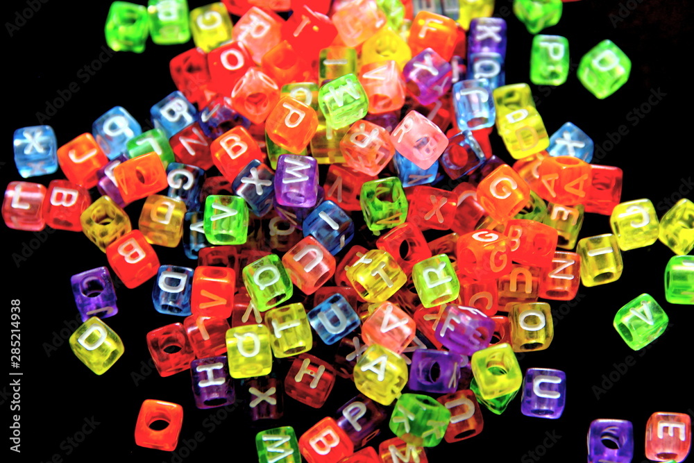 Engish letter on colorful cubic beads isolate on black background.