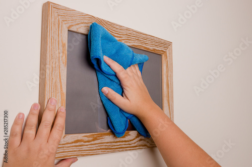 Maid dusting picture frame. Housekeeper doing domestic chores and cleaning.