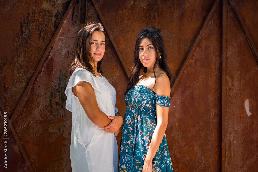 Complicity moment, relaxed women enjoying sun in front of a rusty metal gate , enjoying beautiful nature, freedom and life at campaign. Concept of vacations, freedom, friendship, happiness. Complicity moment, relaxed women enjoying sun in front of a rusty metal gate , enjoying beautiful nature, freedom and life at campaign. Concept of vacations, freedom, friendship, happiness.