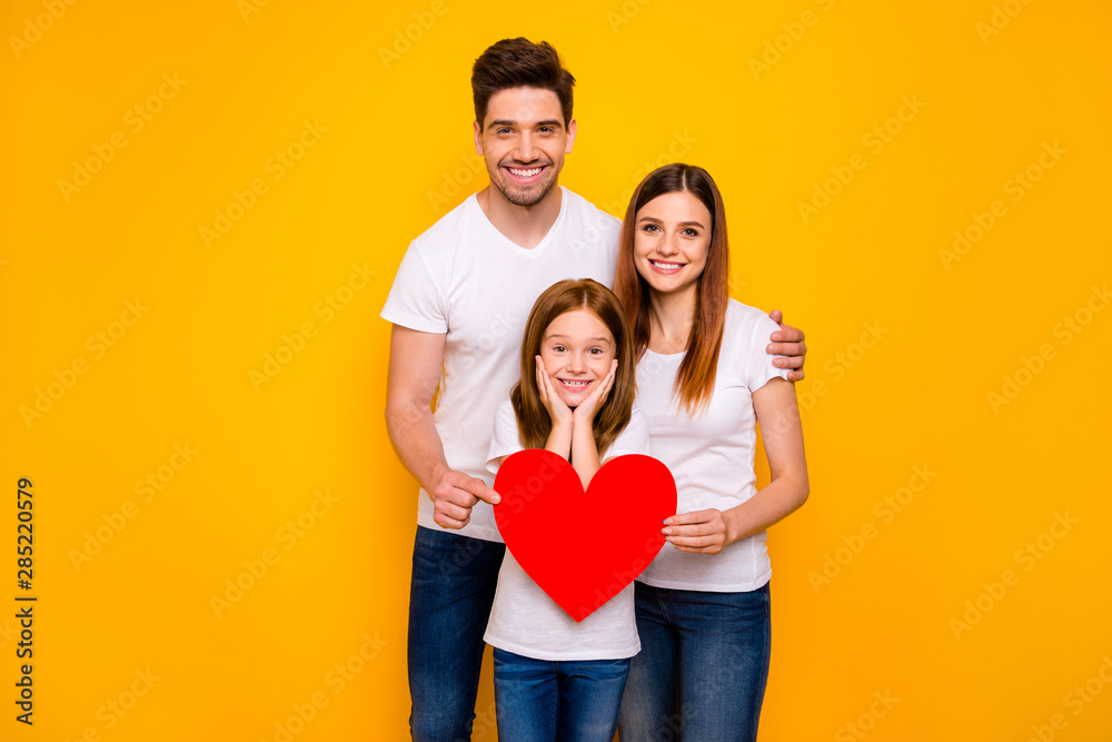Portrait of three nice attractive charming lovely careful cheerful cheery tender amazed healthy person holding in hands big large heart isolated over bright vivid shine yellow background