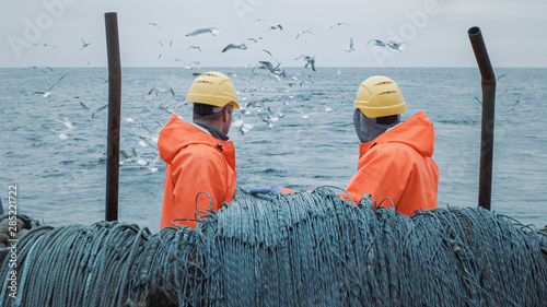 Crew of Fishermen Work on Commercial Fishing Ship that Pulls Trawl Net.