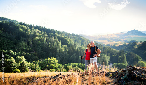 Senior tourist couple with backpacks hiking in nature, resting. photo