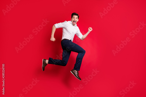 Full length body size photo of quickly running man hurrying up urgently while isolated with red background