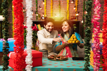 Indian couple with diya, sweets and gifts while celebrating Diwali, Deepavali or Dipavali festival