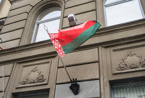 The flag of the Republic of Belarus is fluttering in the wind on the building.