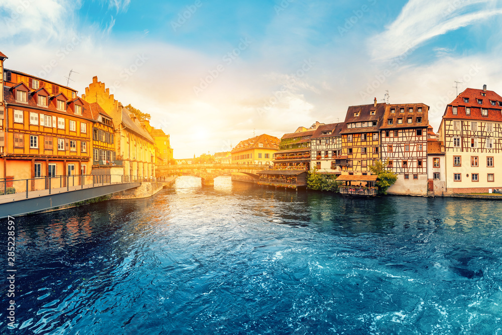 Colorful sunset in the region of Little France in the city of Strasbourg. Famous half-timbered houses, the river Ill and the bridge of St. Martin. Popular tourist destinations in Europe