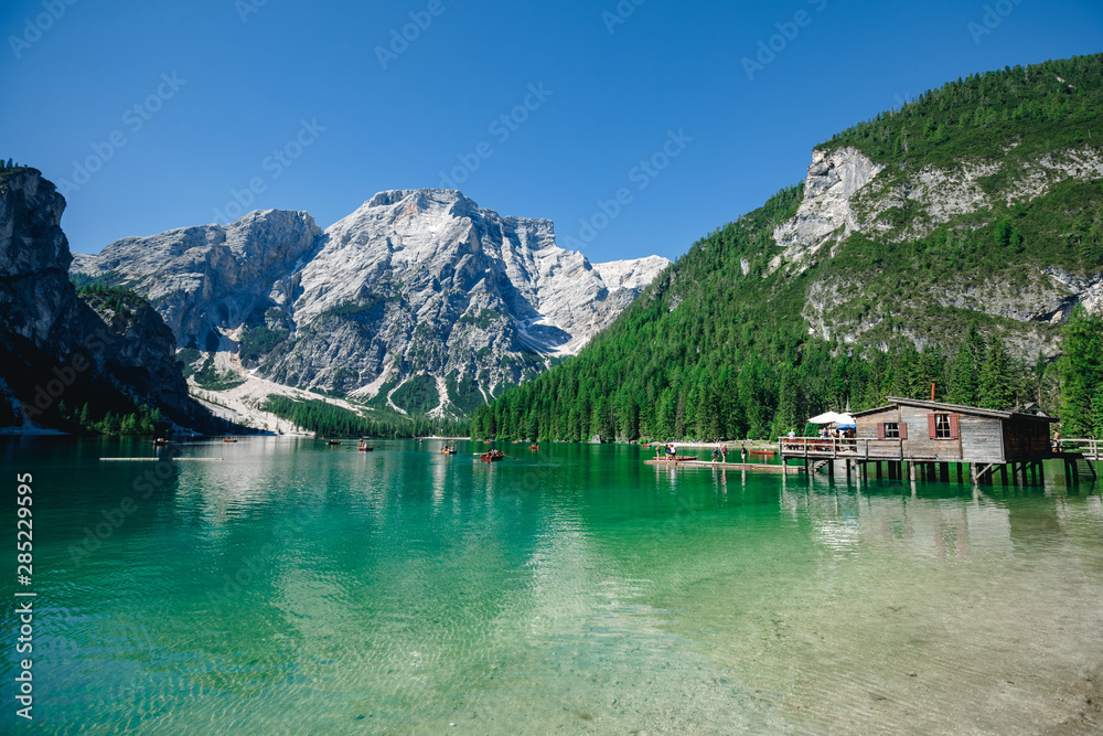 Braies Lake in Dolomites mountains forest trail in background, Sudtirol, Italy. Lake Braies is also known as Lago di Braies. The lake is surrounded by forest which are famous for scenic hiking trails