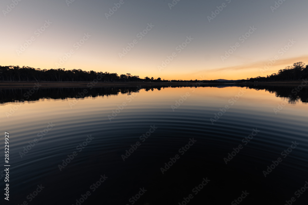 Fototapeta premium Reflection during winter sunset over dam on a clear day in Storm King, Queensland, Australia