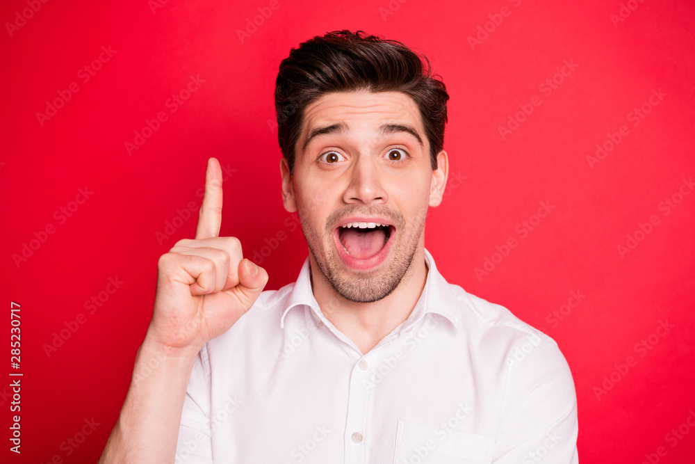 Close up photo of impressed worker raising his index finger screaming wow omg wearing white t-shirt isolated over red background Close up photo of impressed worker raising his index finger screaming wow omg wearing white t-shirt isolated over red background