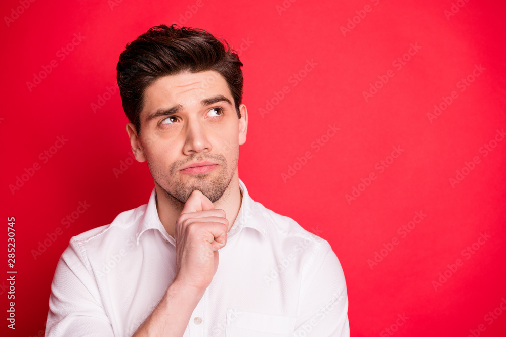Close up photo of minded person touching his chin having thoughts wearing white shirt isolated over red background Close up photo of minded person touching his chin having thoughts wearing white shirt isolated over red background