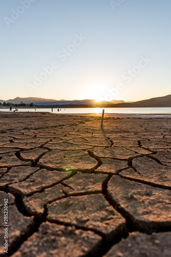 The sun sets setting over a lake it shows the dry cracks in lake bed. On a clear and sunny day in Lake Moogerah, Queensland, Australia