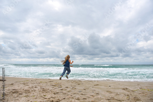 girl running on the sandy beach by the sea