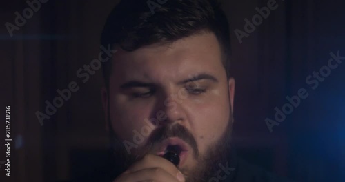 Anamorphic lens, closeup. Low-key shot of black man puffs of smoke 4k