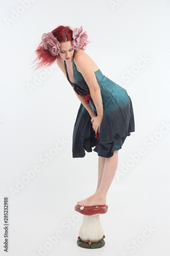 full length portrait of red haired girl wearing fairy costume, posing on a white studio background. photo