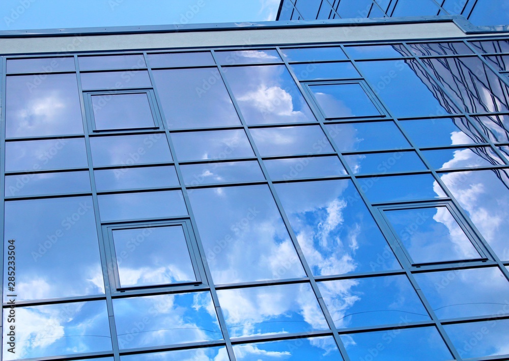clouds reflected in the many mirrored facets of a modern office building clouds reflected in the many mirrored facets of a modern office building