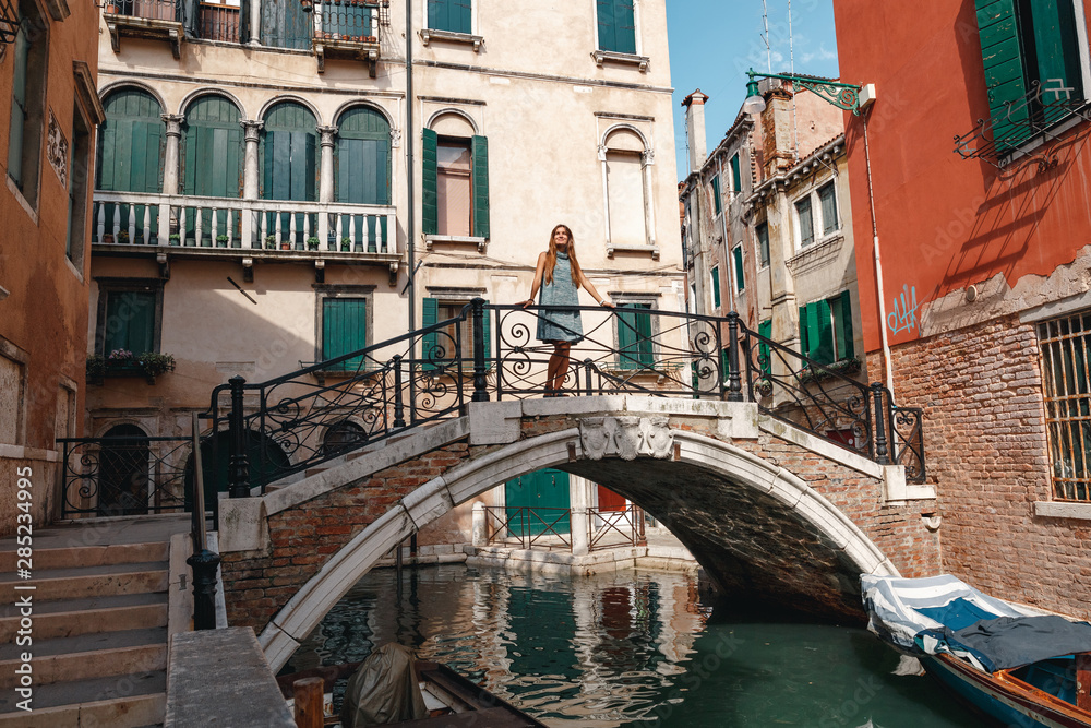 Travel to Italy. Girl standing on the bridge in Venice. Beautiful well-dressed woman posing on a bridge over the canal in Venice, Italy. Europe travel vacation. Woman traveling to Venice