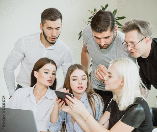 A company of young people having a meeting and watching information on a tablet PC © vagon