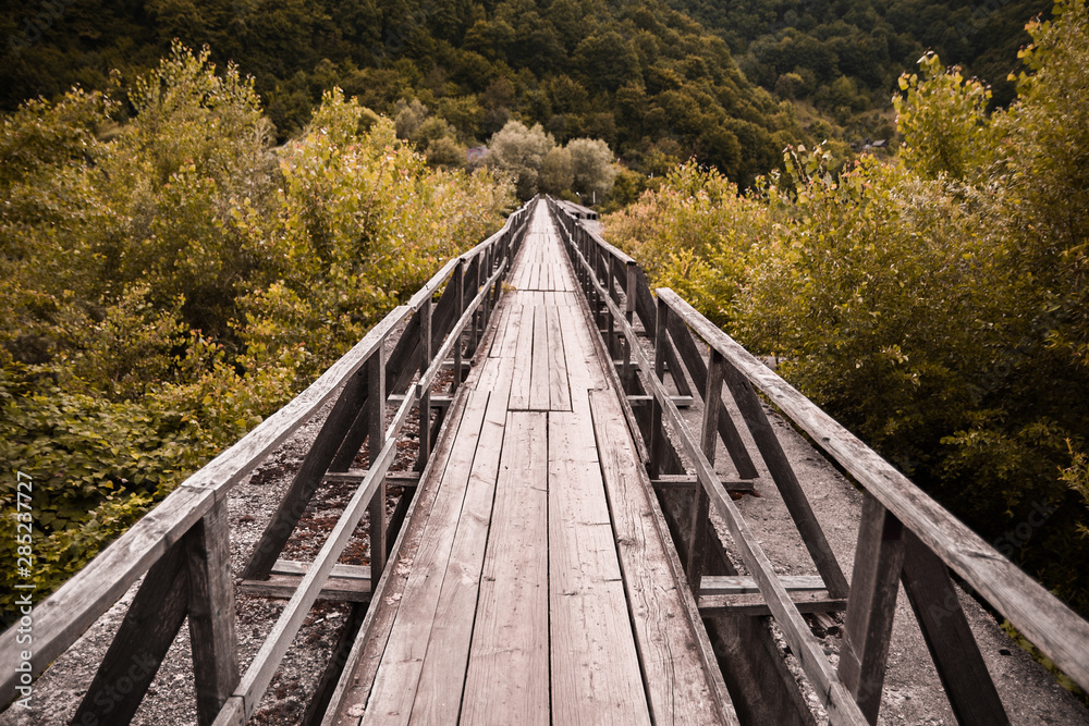 Winding wooden bridge over a river old in deep forest, natural vintage background