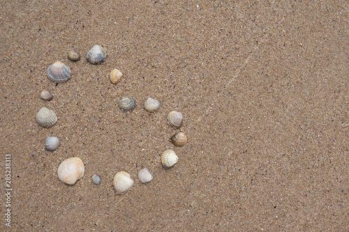  Heart made of shells on the sand by the sea. Symbol of love.