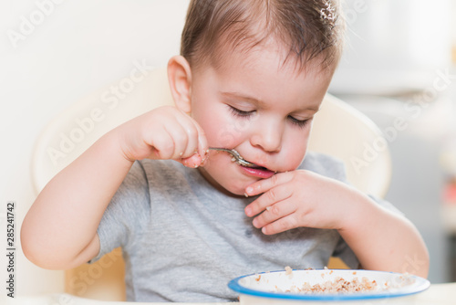 the kid eats buckwheat porridge in the kitchen