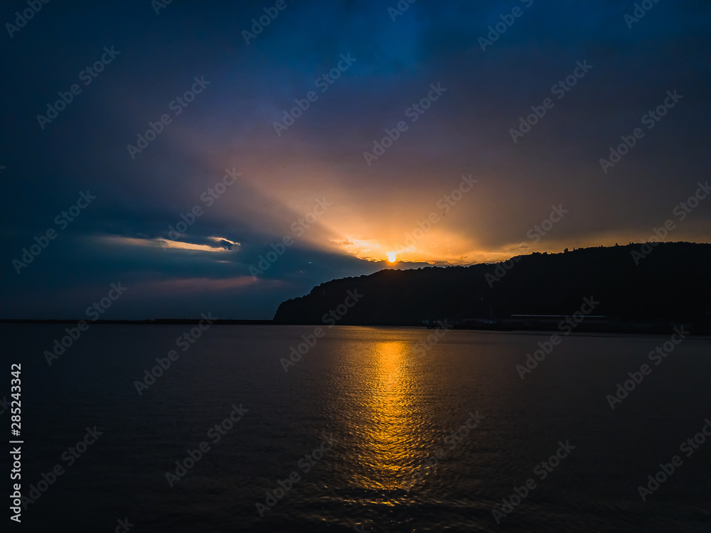 Fototapeta premium Beautiful orange sunset over the sea on a summer evening under a cloudy sky.