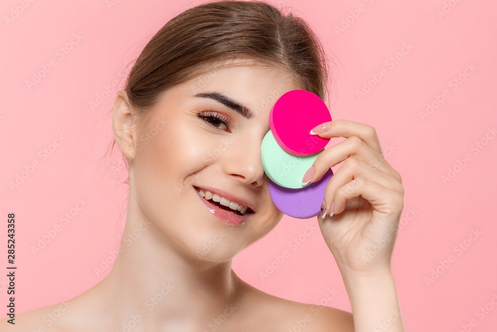 Beautiful model holds cotton sponges of different colors close to face. Beautiful model holds cotton sponges of different colors close to face.