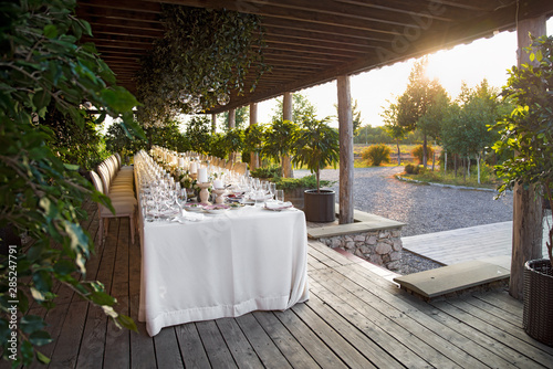Outdoor wedding celebration at a restaurant. Festive table setting, catering. Wedding in rustic style in summer, beautiful small bouquets on a table. © izikmd