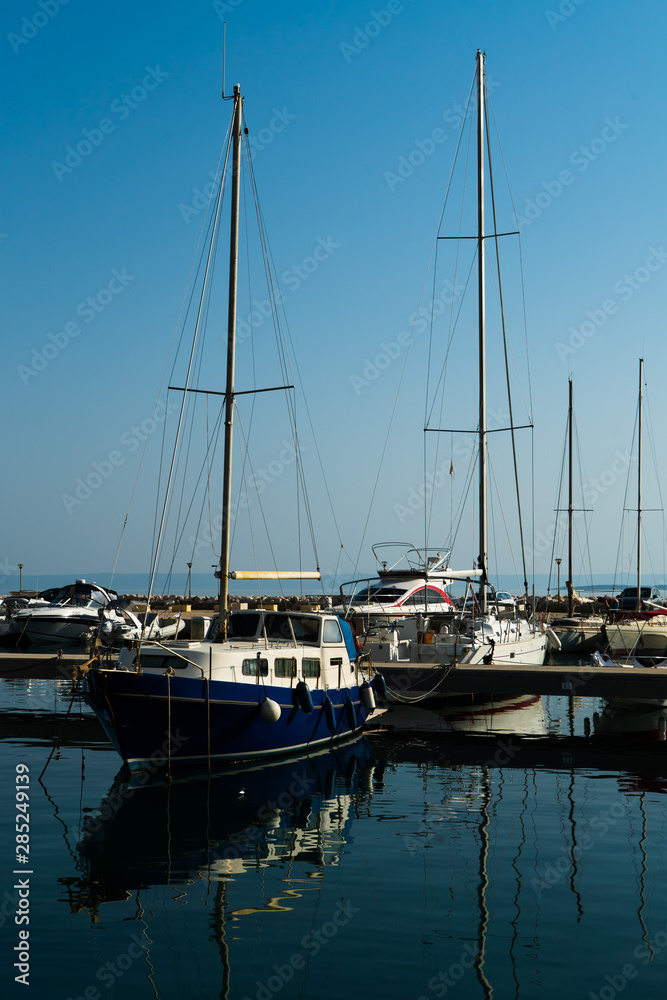 sailing boats with masts in sea dock reflecting in water