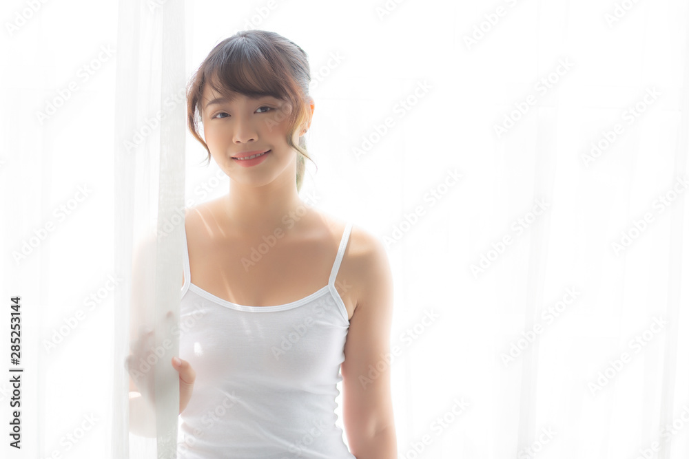 Portrait of beautiful young asian woman standing the window and smile while wake up with sunrise at morning, girl happy with freshness and cheerful, lifestyle and relax concept. Portrait of beautiful young asian woman standing the window and smile while wake up with sunrise at morning, girl happy with freshness and cheerful, lifestyle and relax concept.