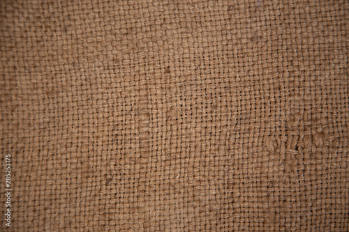 Dark brown background from a textile material with wicker pattern  closeup. Structure of the bronze fabric with texture.