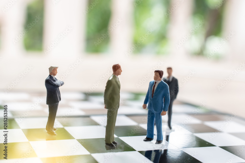 Business strategy. Miniature businessman standing on chessboard with chess pieces. Business strategy. Miniature businessman standing on chessboard with chess pieces.