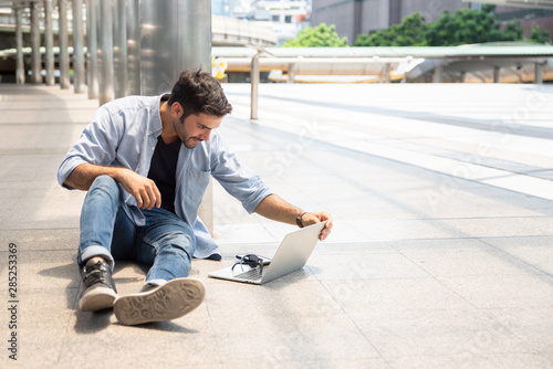 Full Length Of Businessman Using Laptop While Sitting On Footpath