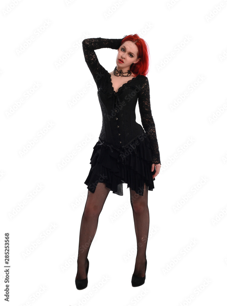 full length portrait of a red haired girl wearing a black gothic gown, Standing pose on a grey studio background. full length portrait of a red haired girl wearing a black gothic gown, Standing pose on a grey studio background.