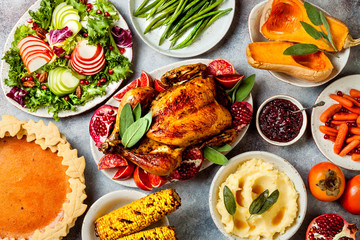 Thanksgiving dinner table with roasted whole chicken or turkey, green beans, mashed potatoes, cranberry sauce and grilled autumn vegetables. Top view, overhead.