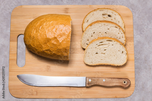Chleb na desce do krojenia. Pół bochenka chleba i trzy kromki. Przygotowywanie kanapek. © art08